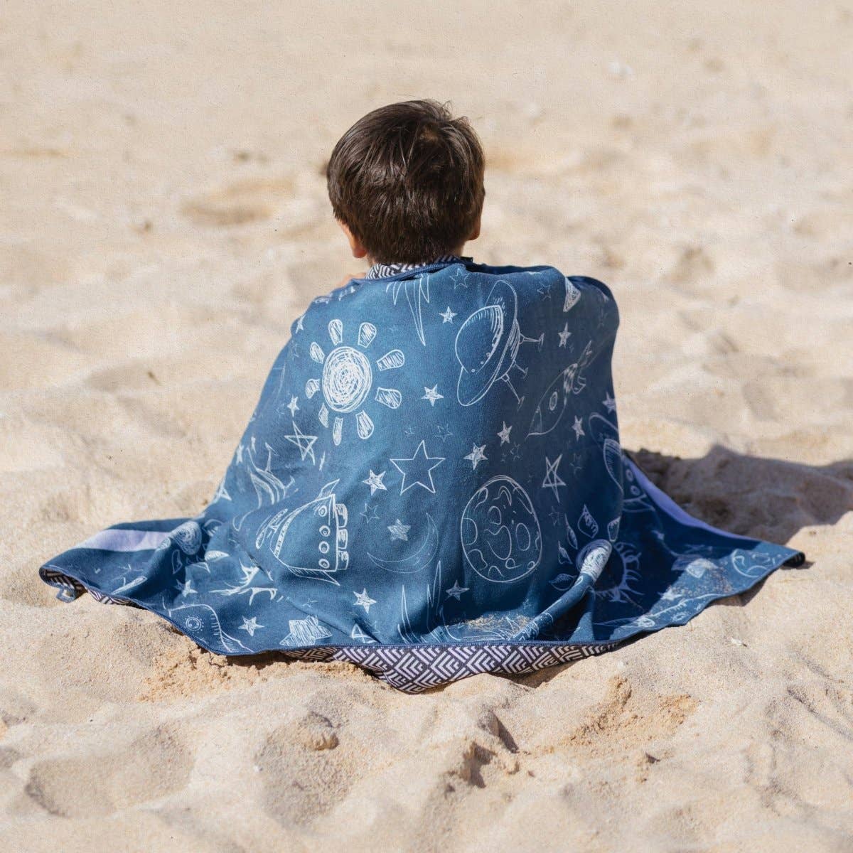 Kind am Strand mit dem leichten und schnelltrocknenden Woods & Waves Strandtuch Galaxy Quest