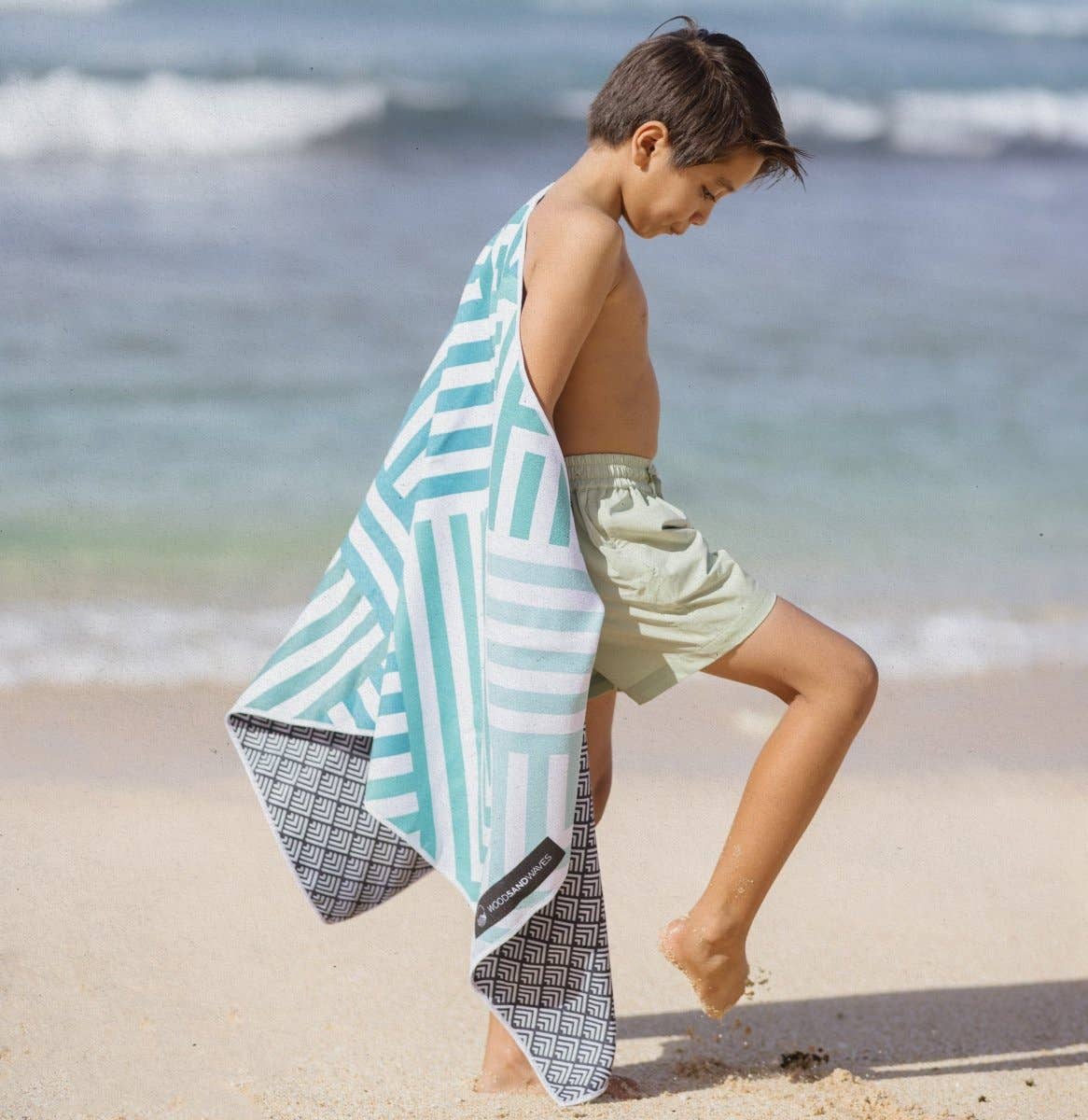 Kind am Strand mit dem leichten und schnelltrocknenden Woods & Waves Strandtuch Mint Relaxation